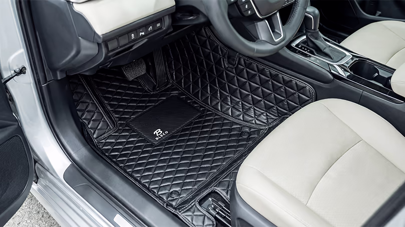 فرش أرضية ليزر Laser Floor Mats في الدمام – اسار أوتو | تغطية كاملة وتصميم فاخر فرش أرضية ليزر بجلد أسود مبطن بتصميم الماسي تغطي أرضية السيارة بالكامل مع مقعد أبيض في الخلفية.