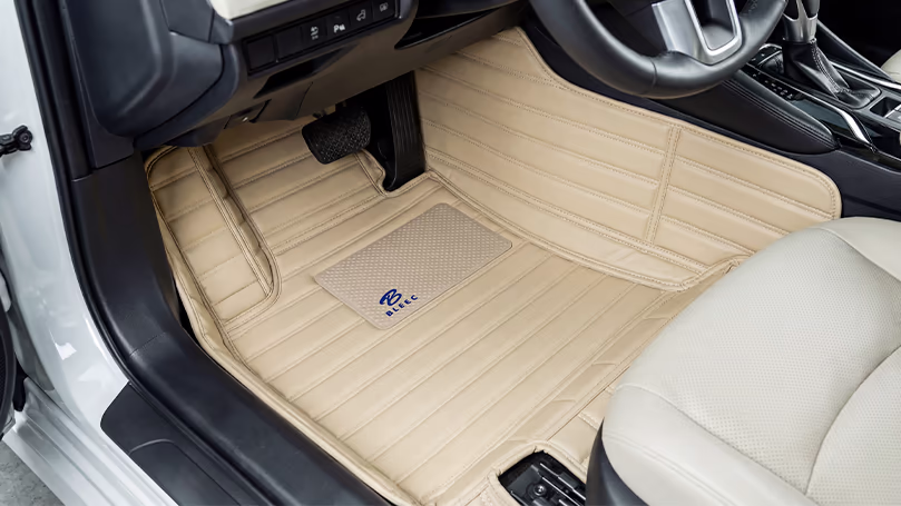 فرش أرضيات فاخرة Luxury Floor Mats في الدمام – اسار أوتو | جلد بيج راقٍ لسيارتك فرش أرضية فاخرة بجلد بيج بخطوط أنيقة وشعار Bitec تغطي أرضية السيارة بالكامل مع مقعد بيج في الخلفية.